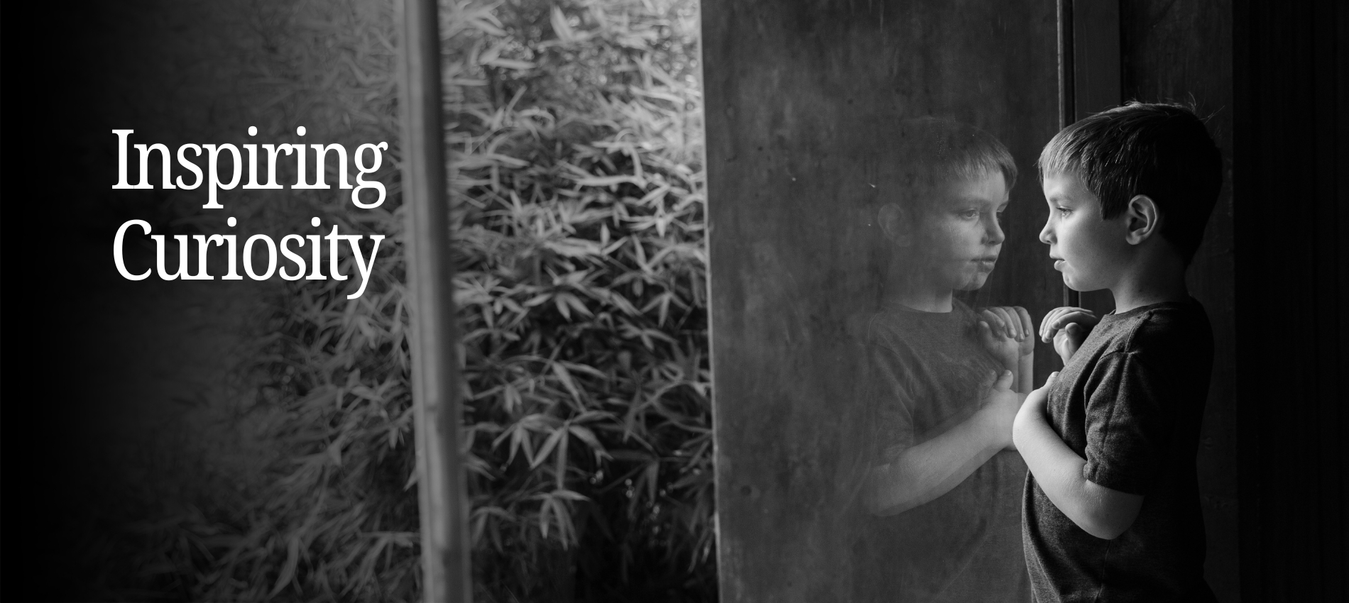 Boy looking through a window with reflection appearing
